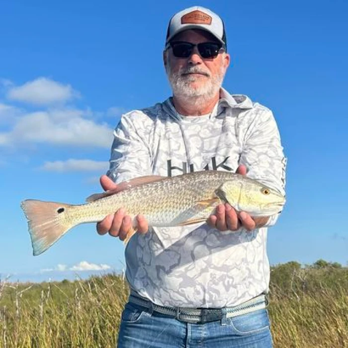 A man holding a redfish caught during a fishing trip.