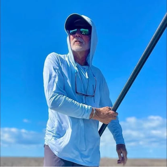 A fisherman using a fishing rod in the open water under a blue sky.