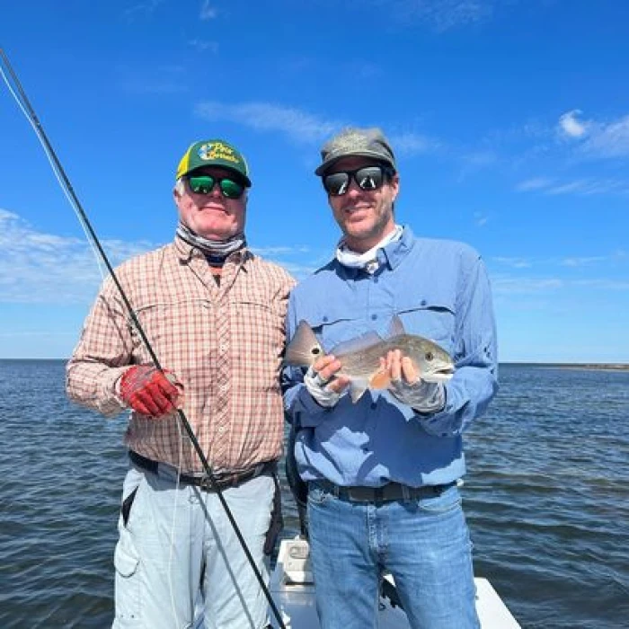 Two men holding a fish while fishing.